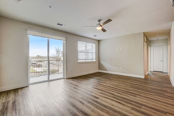 A room with a sliding glass door leading to a balcony, hardwood floors, and a ceiling fan. at Aurora Watson Branch, Mansfield, TX
